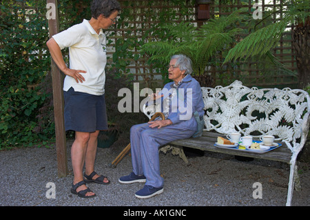 Alte Mutter und Erwachsene Tochter sprechen im Garten Stockfoto