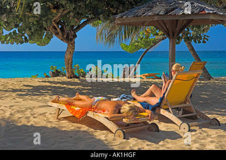 Touristen am Sandstrand unter Palmen mit Meer und blauer Himmel Stockfoto