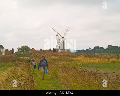 Wanderer auf dem Weg über die Salzwiesen durch die Windmühle am Cley nächste Meer Norfolk England UK Stockfoto