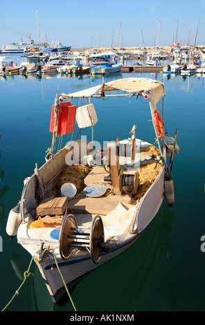 Ein kleines Fischerboot im Hafen von Rethymnon Kreta The Rethymnon-Piräus Fähre macht Rauch oben links. Stockfoto