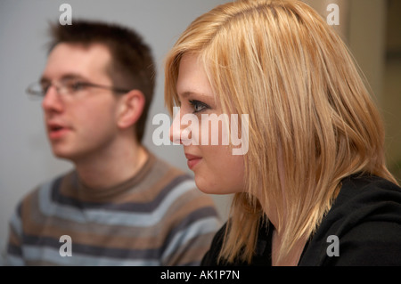 blonde behaarte junge Frau sitzt neben dunkelhaarigen jungen Mann mit Brille jemand anhören Stockfoto