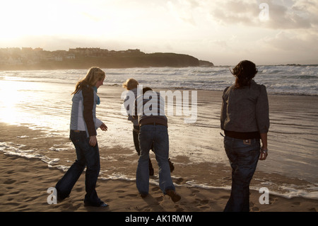 Eine Gruppe von Teenagerstudenten, die an einem Strand herumschwirren Bei Sonnenuntergang schiebt sich gegenseitig ins Meer und macht Spaß Nicht soziale Distanzierung genießen das Leben Stockfoto