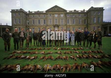 Shooting Party. Die Tasche im Burley House, Burley on the Hill 1980s Rutland. Alle am Ende der Tage Fasanenschießen mit Haus im Hintergrund. OP Stockfoto