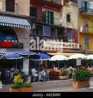 Attraktive Cafés und Restaurants und Personen Speisen unter Fransen Sonnenschirme an der Uferpromenade in Villefranche Südfrankreich Stockfoto