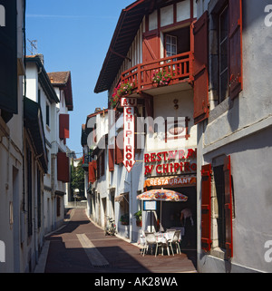 Schmale Seitenstraße und Restaurant "Chipiron" mit Tisch und Stühlen außerhalb St-Jean-de-Luz-France Stockfoto