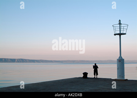 Einsame Gestalt eines Mannes Linie Angeln vom Kai der Makarska Hafen von Dawn Dalmatien Kroatien Stockfoto