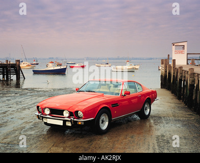 Rot Aston Martin DBS Sportwagen am Hafen Slipanlage mit Booten im Hintergrund. Britische 1980 klassische Kfz. Stockfoto