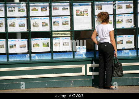 Eine Frau betrachten Immobilien zum Verkauf in das Fenster ein Immobilienmakler, Nominierungsparteitag, Essex, England, UK. Stockfoto