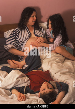 Eine schwangere Mutter im Bett mit ihren Kindern, London, UK. Stockfoto