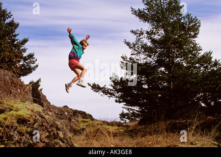 Ein zehn Jahre alter Junge springt über Felsen an einem sonnigen Tag Stockfoto