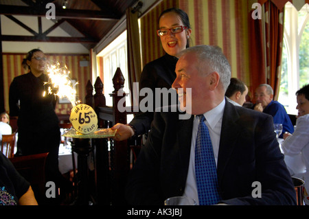 Großvater Geburtstag 65 fünfundsechzig Jahre Ruhestand Familienrestaurant glücklich Feier Mann Kellnerin Baby Kuchen Feuerwerk Stockfoto