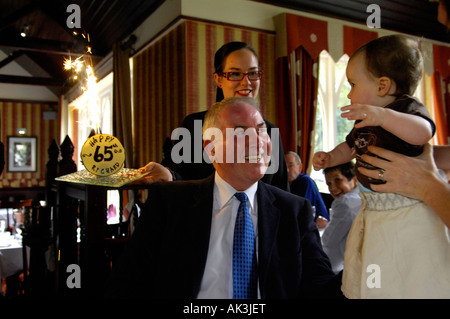 Großvater Geburtstag 65 fünfundsechzig Jahre Ruhestand Familienrestaurant glücklich Feier Mann Kellnerin Baby Kuchen Feuerwerk Stockfoto