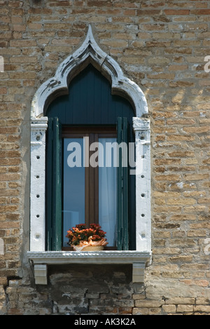 Altes gewölbtes Fenster in Honig farbigen Ziegelwand mit roten Blumen im Korb Venedig 2005 Stockfoto