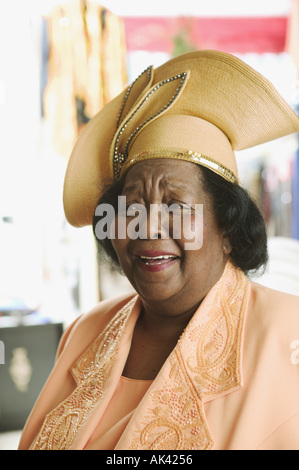 Eine ältere Frau trug einen gelben Kleid und Hut Stockfoto