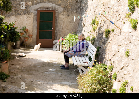 eine alte Dame sitzt in ihrem Garten im Süden von Frankreich mit ihrer Katze