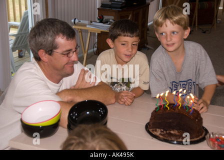 Familie Geburtstag, Papa mit zwei jungen, die Schokoladen-Kuchen mit Kerzen zu betrachten. Stockfoto