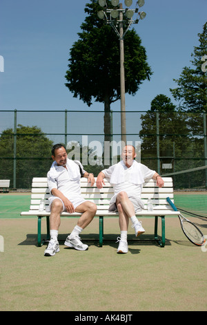 Zwei reife Männer auf Bank Tennisplatz Stockfoto