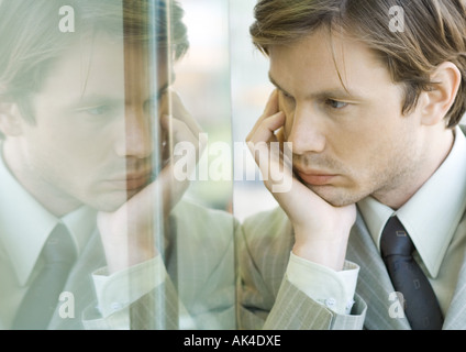 Geschäftsmann hielt Kopf, Gesicht spiegelt sich im Fenster Stockfoto