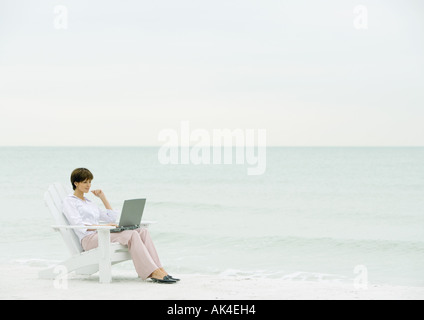 Frau mit Laptop am Strand Stockfoto