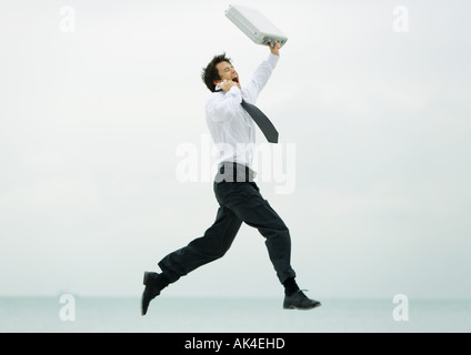 Geschäftsmann, laufen und springen, mit Handy und Aktenkoffer Stockfoto