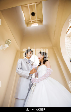 Braut und Bräutigam ziehen das Seil von bell Stockfoto