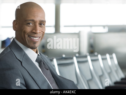 Geschäftsmann, sitzen im Flughafen-Lounge, lächelnd in die Kamera Stockfoto