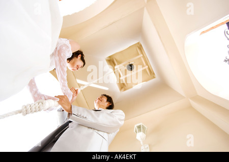 Braut und Bräutigam ziehen am Seil der Glocke, niedrigen Winkel Ansicht Stockfoto