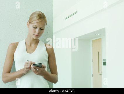 Frau mit elektronischer Organizer im Flur des Bürogebäudes Stockfoto