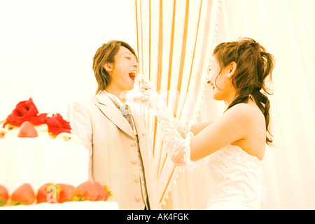 Braut, die Fütterung des Bräutigams ein Stück der Hochzeitstorte Stockfoto