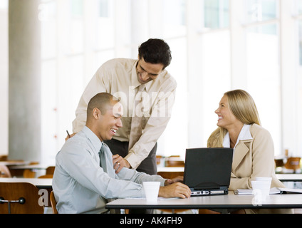 Drei junge Führungskräfte, die lachend in cafeteria Stockfoto