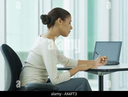 Frau sitzt am Schreibtisch, schreiben Stockfoto
