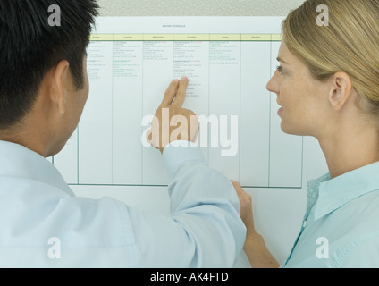 Zwei Kollegen Blick auf Tabelle an Wand Stockfoto