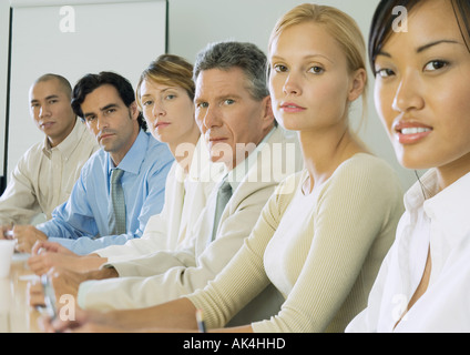 Reihe von Geschäftsleuten, die am Tisch sitzen Stockfoto