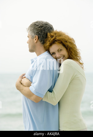 Frau umarmen Mann von hinten, Meer im Hintergrund Stockfoto