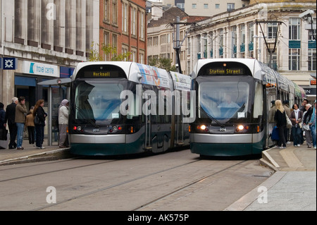 Menschen immer ein- und Ausschalten zwei Straßenbahnen auf dem Marktplatz, Nottingham City Centre Nottinghamshire UK Stockfoto