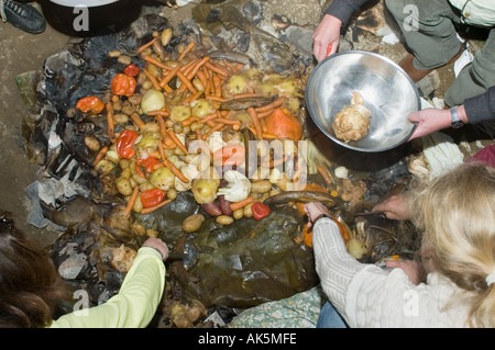 Eröffnung der Grube Ofen bei einem Curanto heißen Kochen in einer Grube Ofen Gemüse und Fleisch kochen auf Steinen Stockfoto