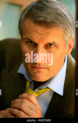 Ein Mann mittleren Alters prüft seine Krawatte in einem Spiegel Stockfoto
