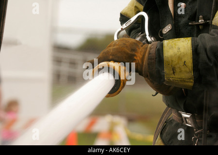 Ein Feuerwehrmann Besprühen mit Wasser aus dem Schlauch auf einem Feuer während einer demonstration Stockfoto