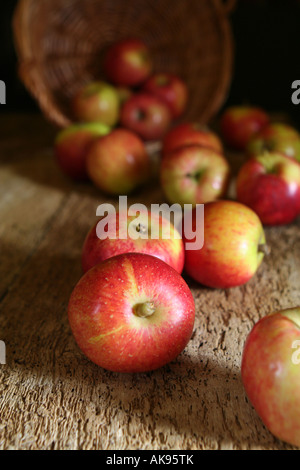 Äpfel aus einem umgedrehten Korb bei schwachem Licht verschütten Stockfoto
