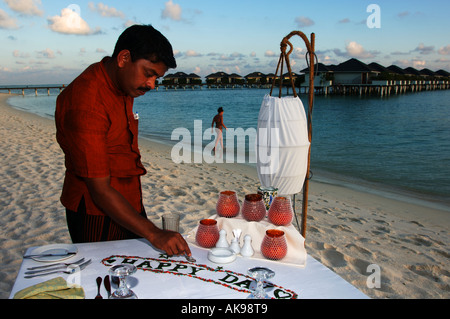 Sun island Resort ein Kellner bereitet einen Tisch am Strand für ein romantisches Abendessen für zwei Personen Stockfoto