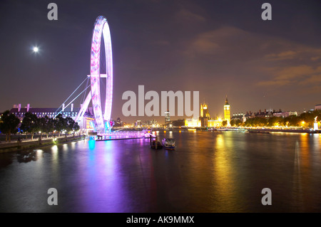 Blick auf das London Eye und die Houses of Parliament entlang der Themse von Hungerford Bridge bei Nacht, London