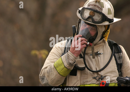 Ein Feuerwehrmann seinen Apparat Atemschutzgeräte bei einer Feuer-Szene ausziehen Stockfoto