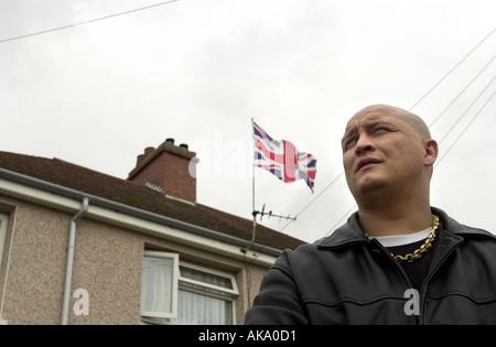 Ein Skinhead steht vor einem Haus, das die Union Flag UK fliegen Stockfoto