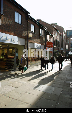 Am frühen Morgensonne wirft lange Schatten, wie Menschen durch Coppergate Shopping Mall in York Fuß Stockfoto