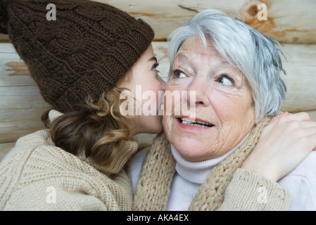 Teenager-Mädchen in Großmutters Ohr flüstern Porträt Stockfoto