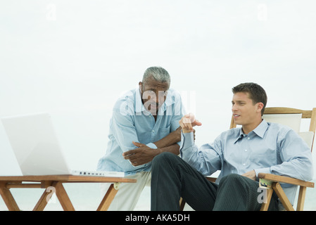Zwei Männer im Freien mit Blick auf Laptop zusammen, Stockfoto
