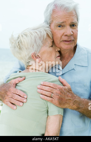 Älteres Paar, Mann Betrieb Frau fest gegen ihn, Blick in die Kamera Stockfoto