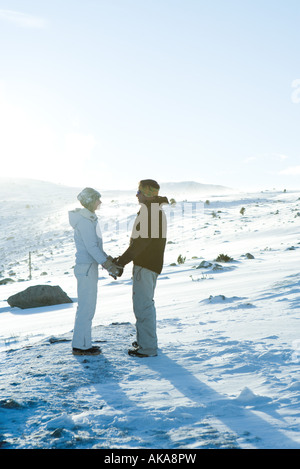 Männlichen und weiblichen stehen im Schnee, Hand in Hand, Angesicht zu Angesicht, in vollen Länge Stockfoto