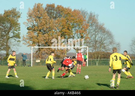 Teenager mit Mannschaftstrikot spielen ein organisiertes Fußballspiel, das von Zuschauern und Eltern Mountnessing Brentwood Essex England beobachtet wird Stockfoto