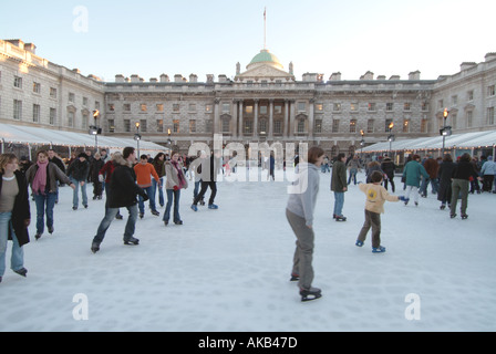 Erwachsene & Kinder Eisläufer mit Hintergrund historischen Somerset House Gebäude & Innenhof auf temporäre Winter Eislaufbahn Strand London, England, Großbritannien Stockfoto